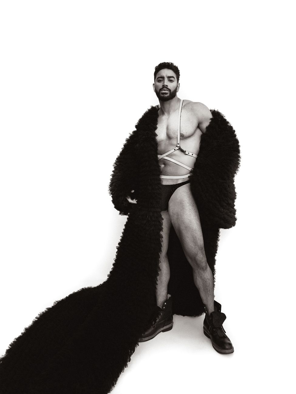 Menswear editorial: a floor-length feathered coat worn open over swim briefs, black and white