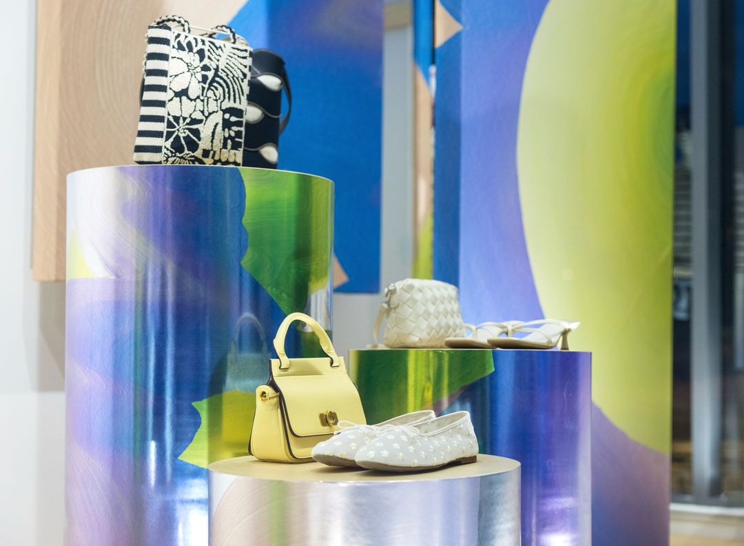 Spring Awakening window display: spring handbags and flats on iridescent plinths against blue and green painted canvases