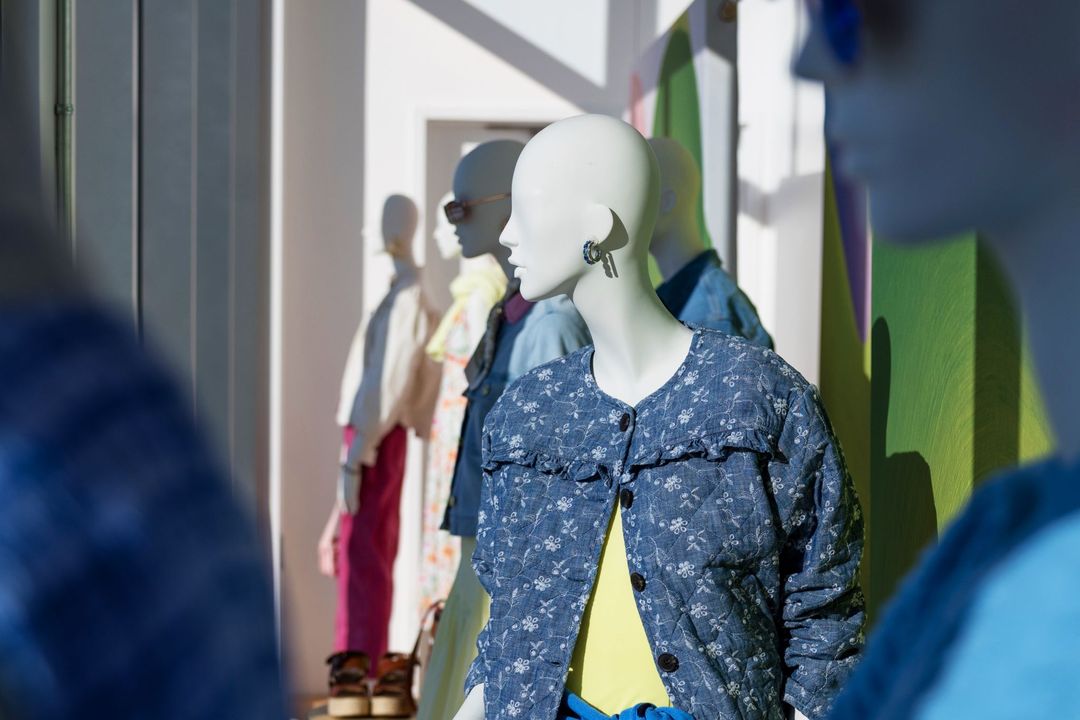 Spring Awakening window display: an embroidered chambray jacket over a yellow top, with more spring looks behind